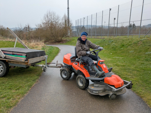 Karl fährt mit dem rasentraktor die schwere Scheibe auf den Platz